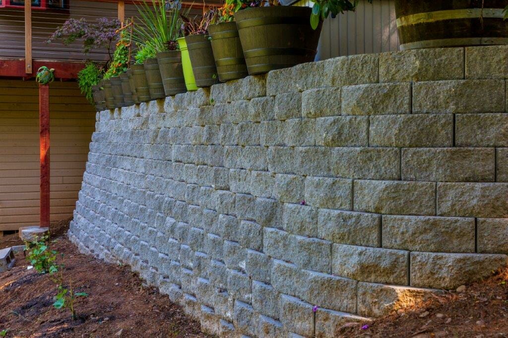 White stone retaining wall installation with potted plants