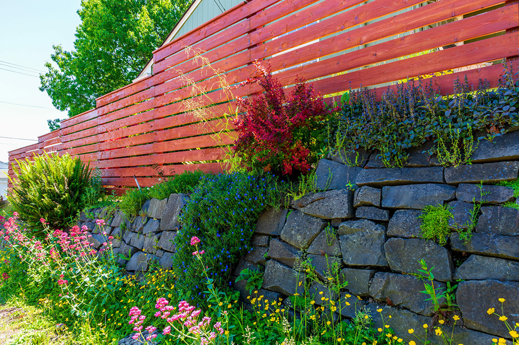 outdoor rock wall with red wooden fence and integrated garden